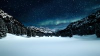 Majestic northern lights dance over snow-covered mountain valley with evergreen forest under starry night sky, creating magical winter landscape.