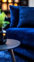 Luxurious royal blue velvet sofa with sequined throw pillows in modern living room setting, warm ambient lighting creates cozy atmosphere with round side table.