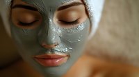 Close up portrait of young woman with green clay mask applied to face during spa treatment, eyes closed and relaxed expression, natural skincare routine.