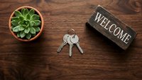 Keys, succulent plant, and welcome sign on wooden table, symbolizing new home ownership, real estate, rental property, or hospitality.