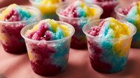 Colorful shaved ice desserts in clear cups with vibrant pink, blue, and yellow layers, perfect for summer treats, frozen beverages, and food photography.