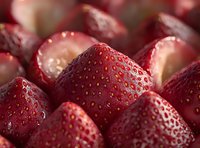 Fresh ripe strawberries cut into pieces showing juicy red flesh and natural texture, arranged in rows for food photography.