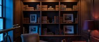 Cozy home library with wooden shelves filled with books, warm lighting, and comfortable seating for reading and relaxation spaces.