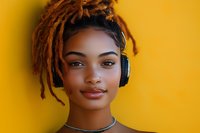 Young African American woman with dreadlocks and wireless headphones smiling confidently against vibrant yellow background, wearing choker necklace and natural makeup.
