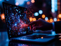 Hand touching laptop screen with glowing digital particles and bokeh lights in dark environment, representing technology, artificial intelligence and digital transformation.