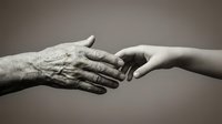 Elderly wrinkled hand reaching toward young smooth hand in touching gesture symbolizing generational connection, care, support and family bonds.