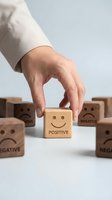 Hand selecting wooden cube with positive smiley face among negative blocks representing optimism choice and mindset transformation for business success.