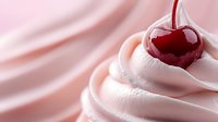 Fresh red cherry on top of soft pink whipped cream swirls against blush pink background, macro food photography highlighting texture and sweetness.