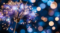 Magical sparkler emitting golden sparks against blurred blue bokeh lights background, creating festive holiday atmosphere. Celebration moment captured in detail.
