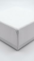 White fitted bed sheet corner detail on neutral background for home textile and bedding product photography.