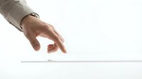 Business hand reaching down to pick up white card from clean surface for professional presentation and corporate communication needs.