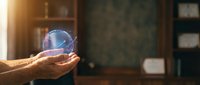Male hands holding glowing blue crystal sphere in warm library setting, symbolizing future vision, innovation, and strategic planning for business concepts.