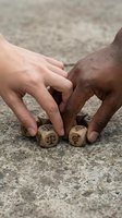 Two diverse hands reaching for wooden dice with legal scales symbols on concrete ground representing justice equality and fair decision making in legal matters.