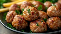 Golden brown meatballs garnished with fresh herbs in cast iron skillet. Homemade comfort food ready for dinner service with pasta or rice accompaniment.