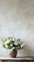 White garden roses in rustic clay pot on wooden table against neutral textured wall background, creating minimalist floral composition with copy space.