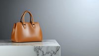 Elegant brown leather handbag on marble surface against gray background. Minimalist luxury fashion accessory with clean composition and copy space.