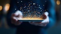 Magical glowing particles floating above smartphone screen held in hands against dark background, creating ethereal digital transformation effect.