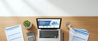 Family insurance policy concept with laptop displaying coverage options, documents, calculator and office supplies on wooden desk for financial planning.
