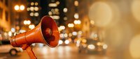 Red megaphone with warm bokeh lights in urban night setting for communication and announcement concepts in marketing campaigns.