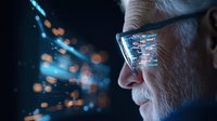 Senior man with glasses looking at futuristic digital data visualization, blue holographic interface reflection shows streaming information and technology concept.