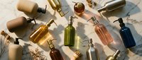 Luxury cosmetic bottles and skincare products arranged on marble surface with natural lighting and shadows for beauty brand marketing campaigns.