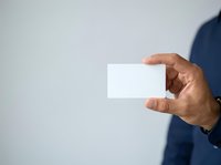 Man in blue shirt holding blank white business card, isolated on light background. Use for corporate branding, networking, and professional marketing materials.