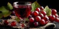 Glass of red wine with fresh grape cluster and vine leaves on rustic wooden surface for winery, vineyard, beverage and culinary presentations.