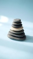 Balanced stack of smooth river stones creating zen tower on soft blue background for meditation and wellness concepts.