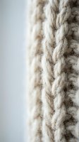Close-up macro shot of natural beige wool yarn twisted rope fibers showing detailed texture and organic weaving patterns for craft and textile projects.