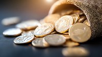 Gold and silver coins spilling from burlap sack on dark surface with selective focus and warm lighting, representing wealth, savings and financial prosperity.