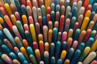 Colorful chalk sticks arranged in rows creating abstract pattern background with vibrant yellow, blue, pink and white pieces standing vertically, macro photography.