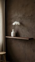 White orchid in ceramic vase on wooden shelf against textured brown wall with neutral curtain, minimalist home decor and interior design styling.