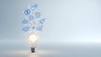 Glowing light bulb with business icons floating above representing innovation, creativity and entrepreneurial ideas for startup success and growth strategies.
