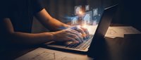 Professional working on laptop with digital technology icons and glowing interface elements in modern office environment for business productivity concepts.