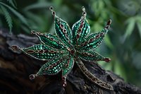Handcrafted emerald green beaded brooch in shape of star flower with copper accents on dark wooden surface against blurred natural background.