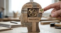 Wooden blocks forming human head profile with motivational words learn grow think innovate and gear mechanism symbolizing personal development mindset.