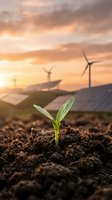 Green seedling sprouting from soil with renewable energy wind turbines and solar panels at sunset representing sustainable development and clean technology.