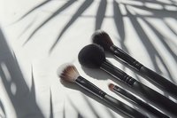 Professional makeup brushes set with palm leaf shadow on white background. Minimal beauty concept for cosmetic product photography and social media content.
