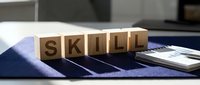 Wooden blocks spelling skill arranged on striped fabric with notebook, representing professional development and competency training for corporate learning programs.