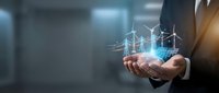 Businessman holding glowing wind turbine hologram with digital grid overlay, representing renewable energy technology and sustainable power solutions for corporate presentations.