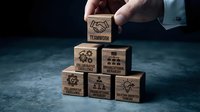 Business professional building wooden blocks with teamwork and collaboration icons representing corporate strategy and leadership development.