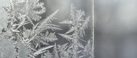 Intricate frost crystals forming delicate ice patterns on glass surface creating natural winter artwork with crystalline formations and frozen textures.
