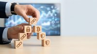 Businessman hands building cybersecurity protection with wooden blocks featuring security icons on modern office desk with digital technology background.