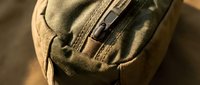 Military tactical backpack in olive green canvas with zipper details and weathered texture for outdoor adventure and hiking gear concepts.