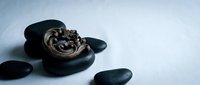Young woman with South Asian appearance receiving relaxing hot stone massage therapy on back, spa wellness treatment.