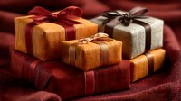 Elegant gift boxes wrapped in warm autumn colors with satin ribbons on textured fabric background for holiday celebrations and special occasions.