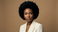 Professional African American businesswoman with natural afro hairstyle wearing beige blazer against neutral background for corporate branding.