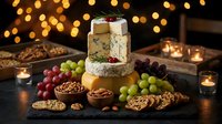 Gourmet cheese platter with grapes, nuts and crackers on wooden board with warm bokeh lights creating festive holiday atmosphere for entertaining.