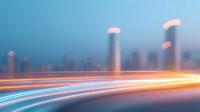 Long exposure light trails on highway at dusk with blurred urban skyline and skyscrapers in background creating dynamic motion effect and modern cityscape atmosphere.