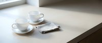 Two white ceramic cups with saucers and spoons arranged on a light surface next to a folded newspaper, ideal for cafe, hospitality, and lifestyle design projects.